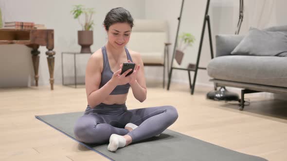 Indian Woman Using Smartphone on Yoga Mat at Home
