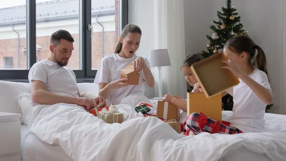 Happy Family with Christmas Gifts in Bed at Home