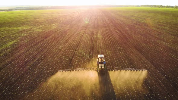 Aerial View of Farming Tractor Spraying on Field with Sprayer Herbicides and Pesticides at Sunset