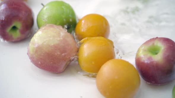 SLOMO of Apples and Oranges in Water on White Backdrop