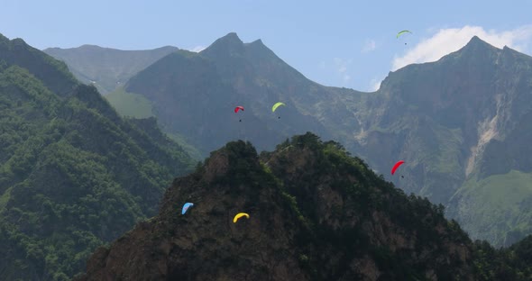 Paragliding Pilots Fly Paragliders Among Clouds and Green Mountains