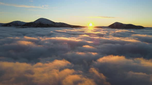 Aerial View of Vibrant Sunrise Over White Dense Fog with Distant Dark Peaks of Carpathian Mountains