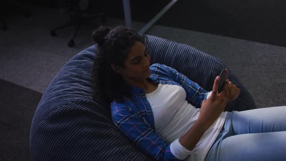 Mixed race woman lying on bean bag taking selfie and smiling