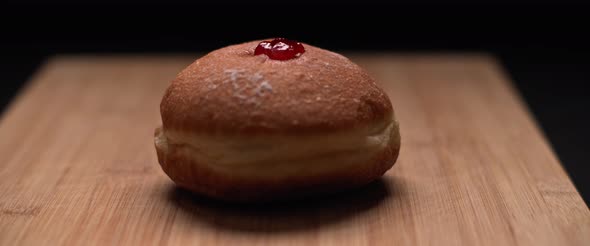 Hanukkah jelly doughnut on a wooden board, slow motion
