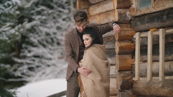 Couple Stands Near a Wooden House