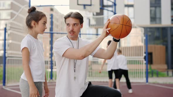 Male Basketball Coach Training Girl How to Throw a Ball to Basket