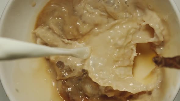 TOP VIEW: Milk And Coffee Mixing In A White Cup - Slow Motion