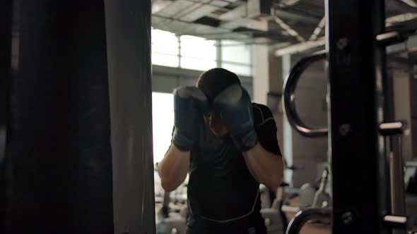 Closeup of an Aggressive Caucasian Man Hitting a Punching Bag in a Gym