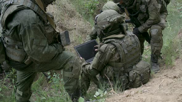 Soldiers in Camouflage in Ambush Military Engineer Uses a Laptop Navigation System Military Action