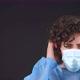 Serious Male Doctor in a Blue Medical Coat Put on a Medical Mask Looking at Camera - VideoHive Item for Sale