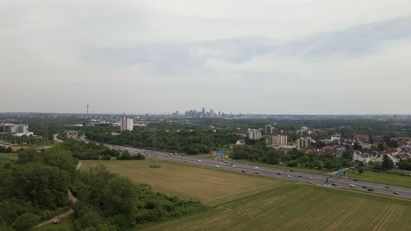 The cityscape of Frankfurt, Germany behind the busy a66 highway on a cloudy spring day. Aerial ascen