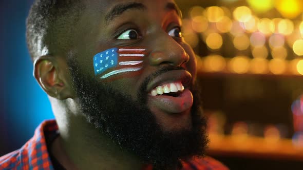 Black Sports Fan With American Flag on Cheek Rejoicing Favorite Team Victory