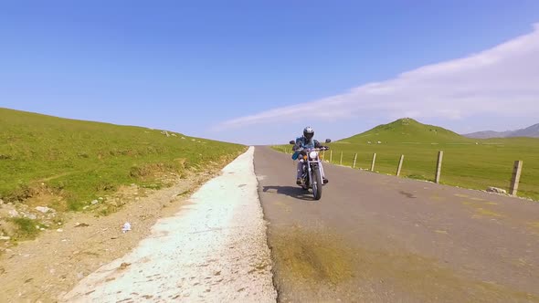 Motorcyclist driving his motorbike on the mountain road in the mountain country side.