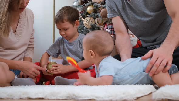 Smiling Boy Plays with Baby Brother in Christmas