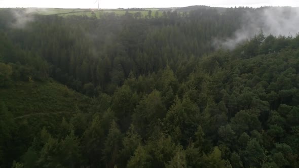 Aerial shot of foggy woodland deep in the countryside, rain pouring down