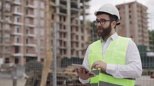 Architect Man Standing with Tablet on the Construction Site and Analyzing Scheme Project Plan