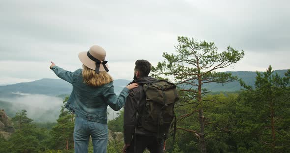 A Woman and a Man are Standing on Top of a Cliff and Looking at Nature