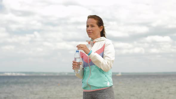 Woman Drinking Water After Exercising on Beach 