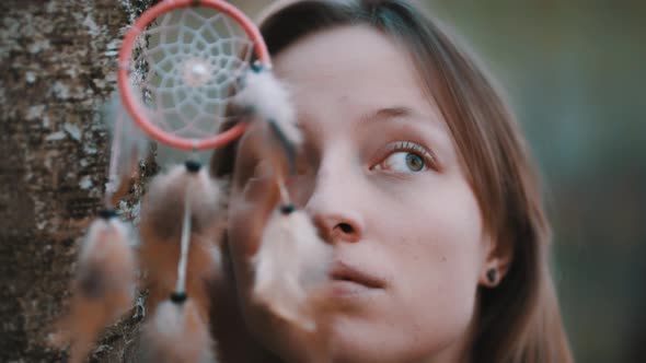 Portrait of Caucasian Woman with Green Eyes Posing in the Forest Near Tree Bark with Dreamcatcher in