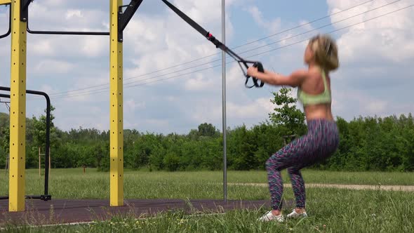 A Beautiful Fit Woman Does Assisted Squats with Jumps at an Outdoor Gym - Closeup