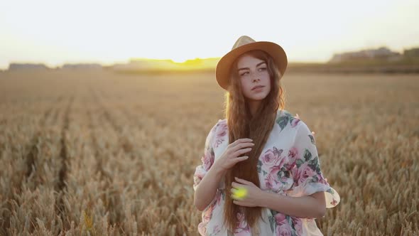 Thoughtful Young Girl Looking Aside and Caresses Her Long Hair Among Wheat