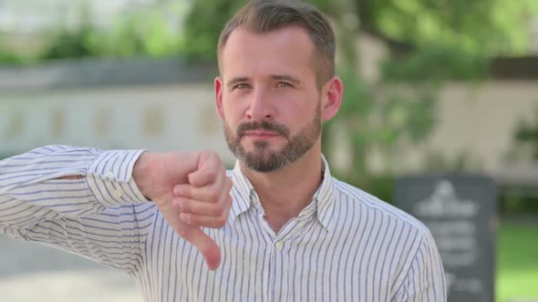 Outdoor Portrait of Thumbs Down Gesture By Middle Aged Man