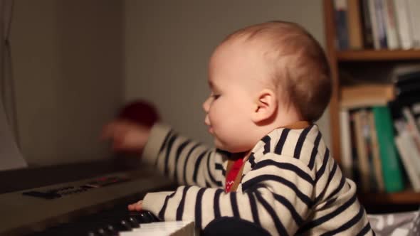 Home movies of a baby in a family wearing a striped sweater to match a piano.