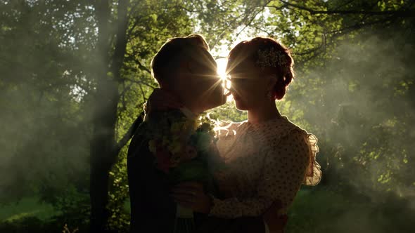 Happy Couple are Standing in Forest in Sun Setting Sun is Shining Into Camera Beautiful Outline on