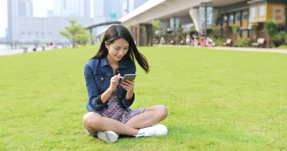 Woman using cellphone and sitting on the lawn