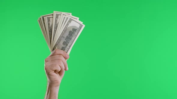 Male Hands Hold a Bundle of Dollar Bills and a Vintage Watch on a Chain Against a Green Screen