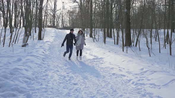 Happy Couple Holding Hands Run On Snow In Winter Park. Slow Motion Snow Sunny Day 2