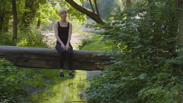 Middleaged Mature Woman Caucasian Lady Athlete in Black Tracksuit Sitting in Summer in Park on Tree