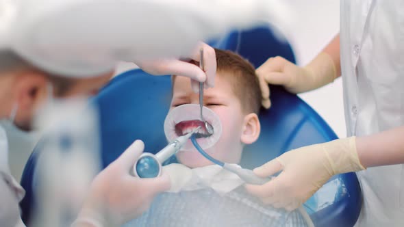 Boy Sit in Stomatology Armchair Surrounded By Medical Staff