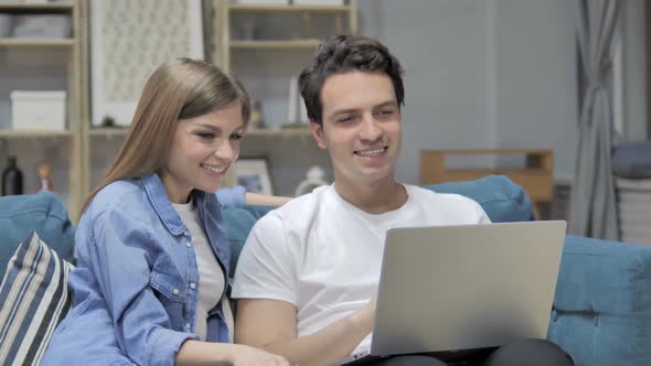 Online Video Chat on Laptop By Young Couple Realxing at Home