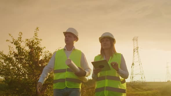 A Group of Engineers at a Highvoltage Power Plant with a Tablet and Drawings Walk and Discuss a Plan