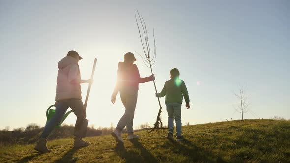 Mom with Two Children Going to Plant a Tree