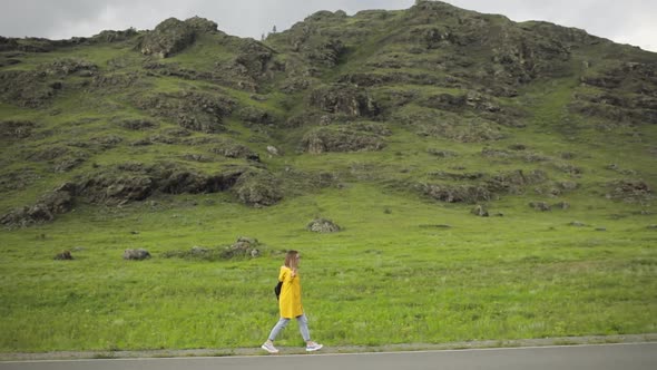 Woman Traveller Hitchhiker Is on Road Trying To Vote To Stop the Car, Side View.