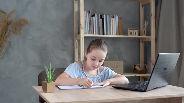 Cute Teenage Schoolgirl Doing Homework Using Laptop at Home