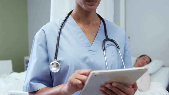 Front view of African american female doctor using digital tablet in ward at hospital 4k