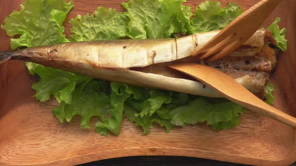 Closeup of a Knife and Fork Cutting a Tasty Grilled White Mackerel Fish