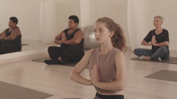 Young Woman Meditating during Group Yoga Class Indoors