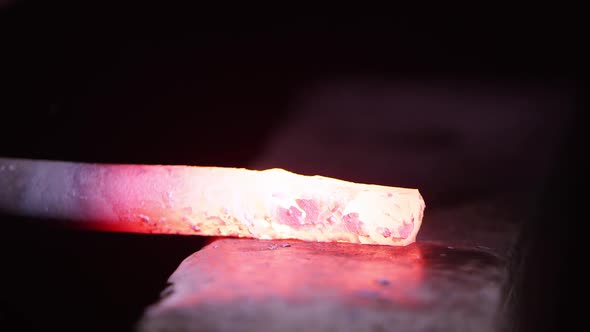 Red hot metal being hammered on anvil up close