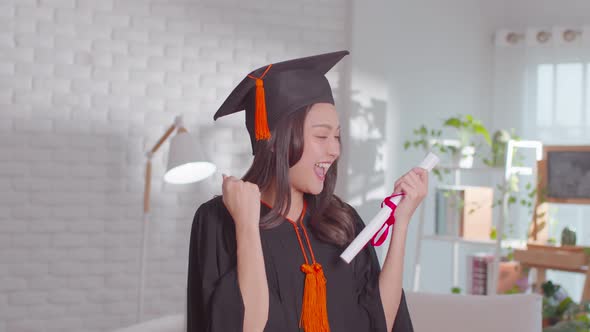 An Asian girl proudly shows her certificate. She is always smile on her graduation ceremony