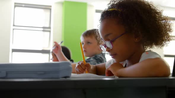 Side view of African american schoolgirl studying at desk in classroom at school 4k