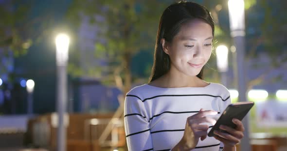 Woman use of smart phone in city at night 