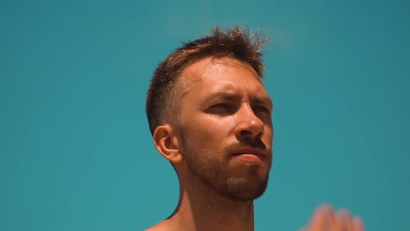 A Young Man Fixes His Hair Against the Blue Sky