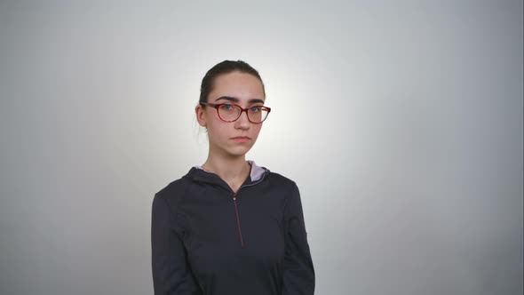 Indifferent Glance of a Girl in Glasses Over White Background