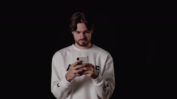 Trendy Young Man using and typing on phone, wide, black background