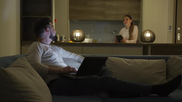Couple talking while using laptop and tablet