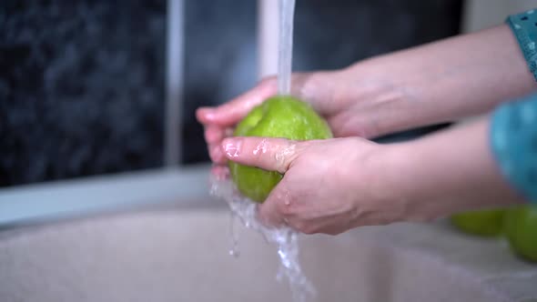 Water is Splashing Over Apples and Apple Slices Woman's Hands Washing Apple with Pure Water From Tap